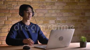 戴着耳机、笔记本电脑和<strong>视频</strong>通话的年轻<strong>韩国</strong>男学生的特写照片